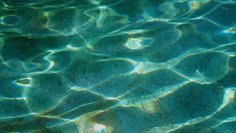 Close-up of murky pool water with ripple patterns and sunlight caustics, ab.. Stock Footage 340041673