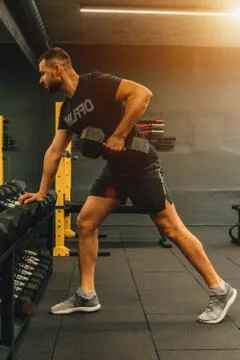 Close up of muscular bodybuilder guy doing exercises with weights in gym. Fit Stock Photos