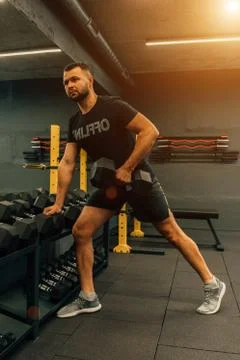 Close up of muscular bodybuilder guy doing exercises with weights in gym. Fit Stock Photos