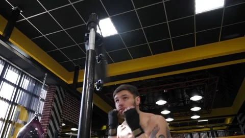 Close-up of muscular man with a bare torso training on a rotating boxing machine Stock Footage 150356775