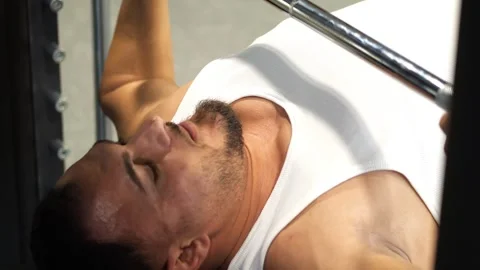 Close-up of a muscular man lying on a weight bench performing barbell bench.. Vidéo 344052899