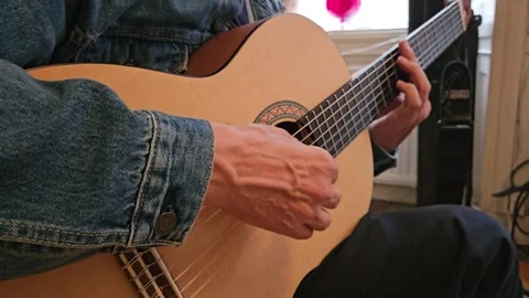 A close-up of a musician s hands playing an acoustic classical guitar at home Stock Footage 344059698