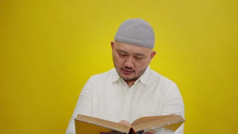 Close-Up of a Muslim Man Reading the Holy Quran, Isolated on a Yellow Background Stock Footage 336994001