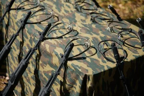 Close-up of the muzzle of black rifles in the woods, leaning against a table. Stock Photos