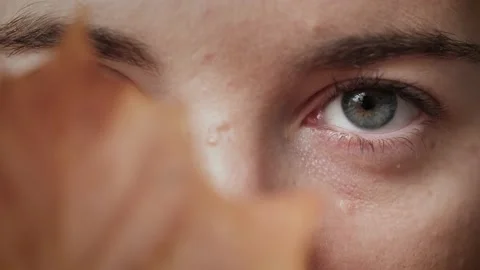 Close up of mysterious Woman's face covered by autumn leaf opening blue eye. Stock Footage 142908641