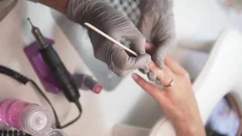 Close-up of a nail technician using a wooden stick to push back the cuticles Stock Footage 311871951