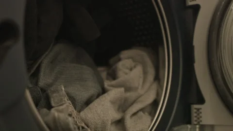 Close up narrow focus: Clothes are put into front load washing machine Stock Footage