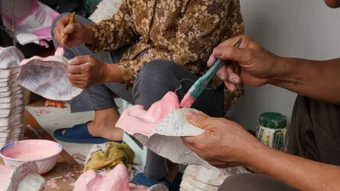 Close up of native vietnamese people using pink paint to color handmade masks Stock Footage 147372731