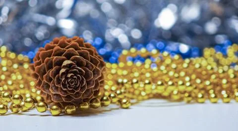 Close up of a natural brown pine cone resting on shiny gold bead garlands w.. Stock Photos