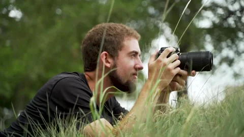 Close-up of a Nature Photographer Lying Down and Taking Pictures With DSLR Video stock 136783376