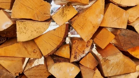 Close-up of neatly stacked split firewood in bright sunlight, showing golden Stock Footage 336428088