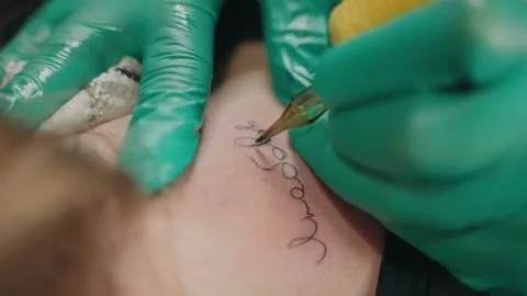 Close-up in neck client master makes tattoo with inscription love, using machine Stock Footage 219549414