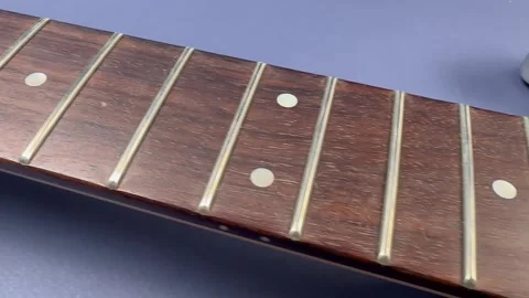 A close-up of the neck of an electric guitar without strings, showing the frets Stock-Footage 317846398