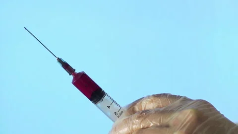 Close-up of a needle from a disposable syringe. A small syringe pushes a red Stock Footage 195253377