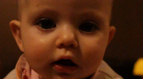 Close up of neutral expression dark eyed baby Stock Footage 35800527