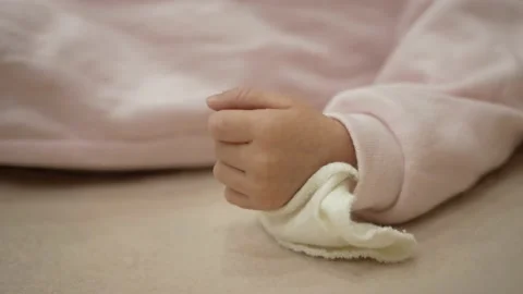 Close up of new born tiny hand on pastel blanket. Unrecognisable kid laying in Video stock 165610493
