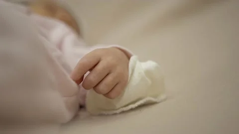 Close up of new born tiny hand on pastel blanket. Unrecognisable kid laying in Stock Footage 165685641