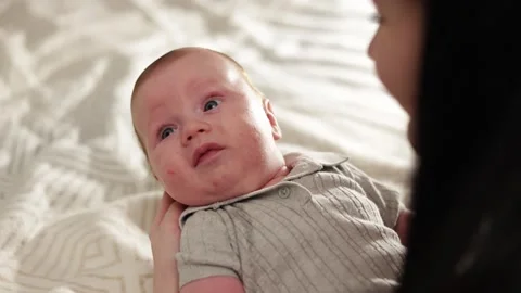 Close-up of a newborn baby being held by a parent, looking curiously to the side Stock Footage 340637041