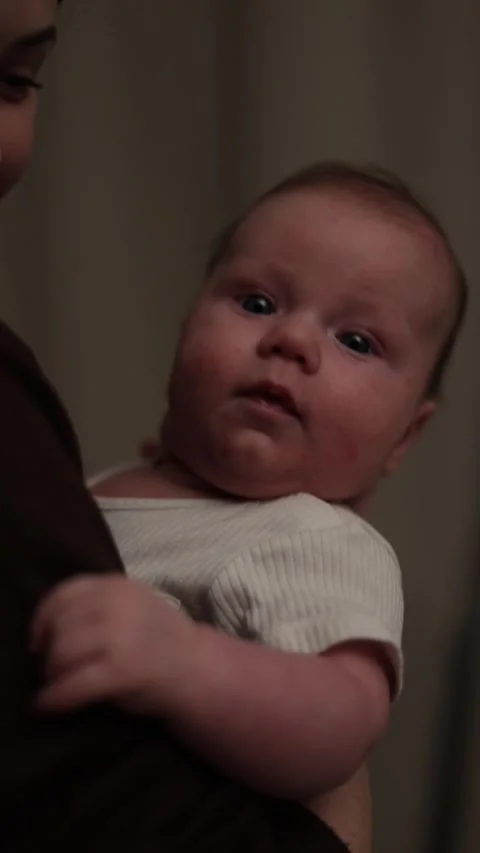 Close-up of a newborn baby being held by a parent, looking curiously at the Vidéo 340637062