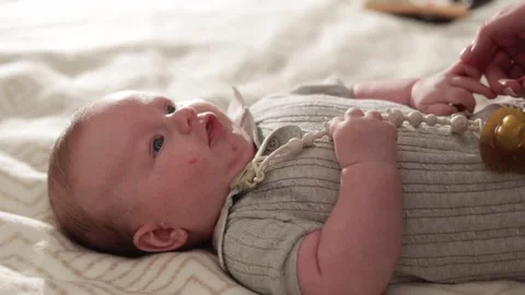 Close-up of a newborn baby lying on a soft blanket with a pacifier clip attached Stockbeeldmateriaal 340629919
