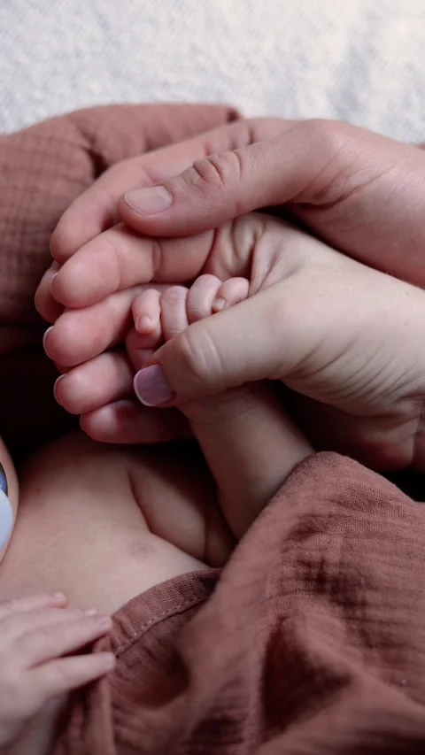 A close-up of a newborn baby’s tiny hand cradled in the loving hands of parents Stock Footage 303600640
