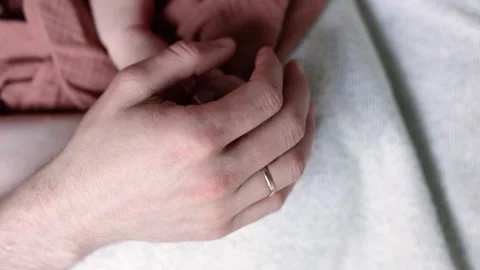 A close-up of a newborn baby’s tiny hand cradled in the loving hands of parents. Stock Footage 303603611