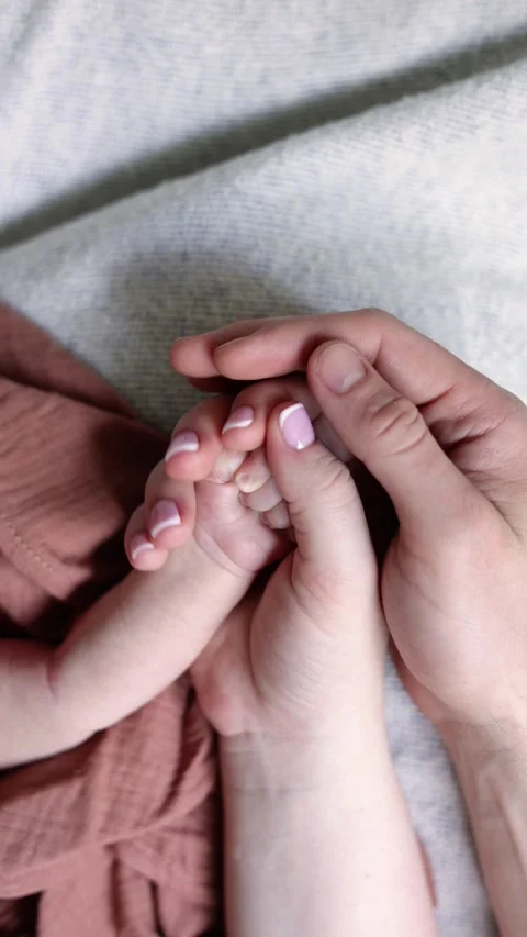A close-up of a newborn baby’s tiny hand cradled in the loving hands of parents Stock Footage 303684330
