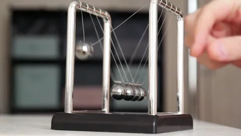 Close-up of Newton's cradle on the table and a man's fingers pulling back one Video stock 260949649