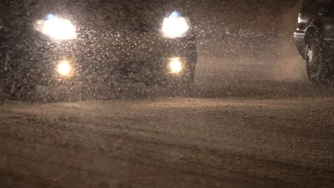 Close-up of a night traffic moving in a snowfall. Headlights in Winter storm. Vidéo 83541701