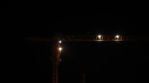 A close-up night view of a tower crane jib illuminated by bright spotlight wo Stock Footage 345020116