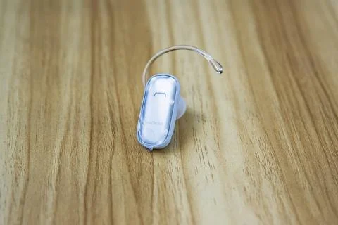 Close-up of a Nokia wireless Bluetooth headset placed on a wooden surface. .. Stock-Fotos