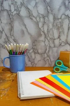 Close up of a notebook with colored paper, scissors, and markers in a blue .. Foto stock