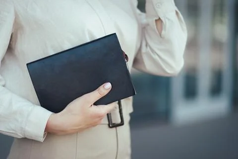 Close-up on a notebook in the hands of a young successful business woman against Stock Photos