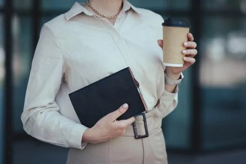 Close-up on a notebook for notes and a paper cup with coffee in the female hands Stock Photos