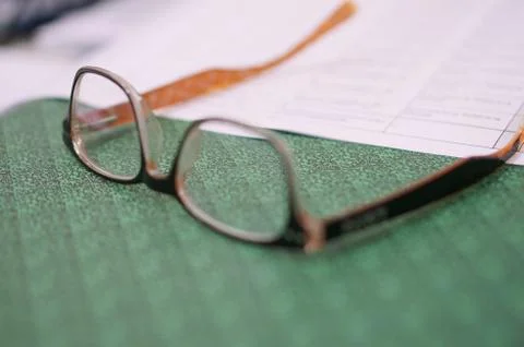 Close notebook, open one sheet and glasses on the office table at workplace Stock Photos