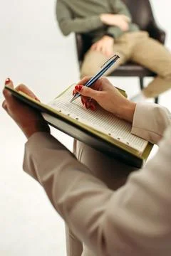 Close-up of a notebook with a pen in the hands of a psychologist taking not.. Stock Photos