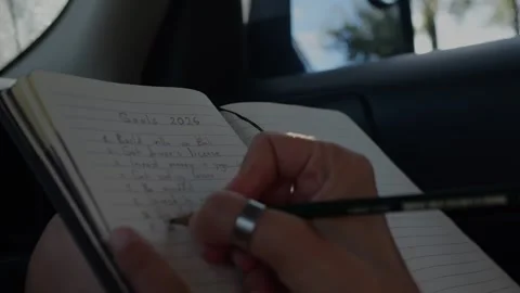 Close-up of a notebook as a woman writes a numbered Goals 2026... Stock Footage 323129099