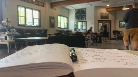 Close up of a notebook with words and writing. Inside a local coffee shop Video stock 164425819