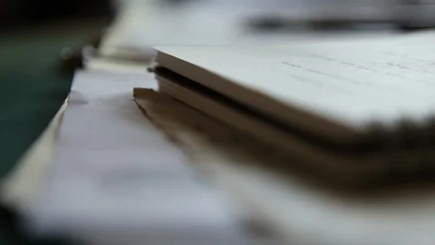 Close-up of notepad/papers on a desk racking focus to a pen Stock Footage 97962546
