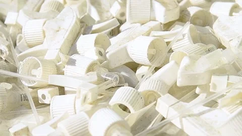 Close-up of numerous white plastic caps and parts of plastic bottles. Video stock 339915392