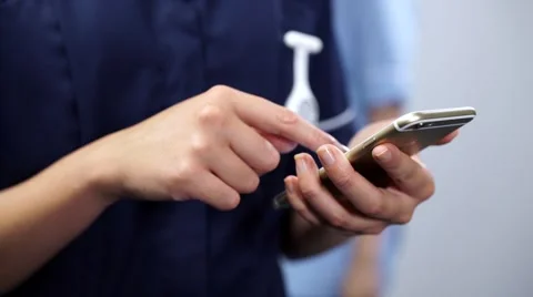 Close up nurse hands using mobile cell phone with colleague passing behind Stock Footage 59087344