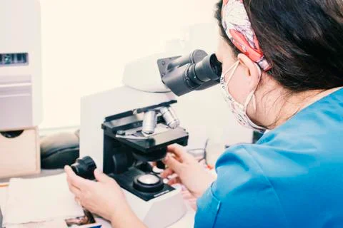 Close-up of a nurse looking through a microscope at samples. Stock Photos