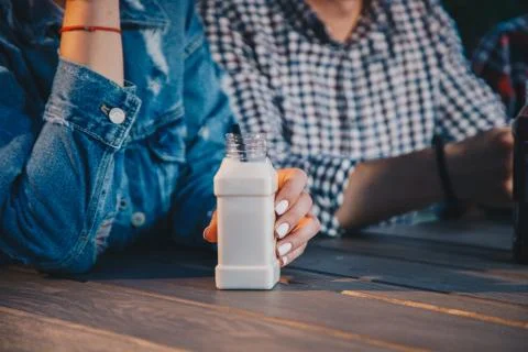 Close up nut milk drink in plastic bottle. Couple in the cafe outdoor. Fresh Stock Photos