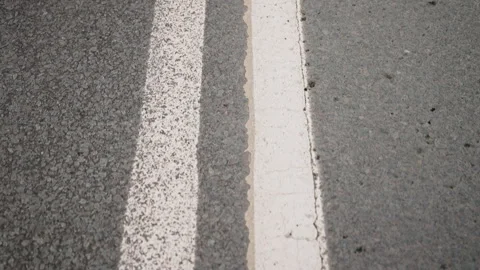 Close-up observation of two parallel white and one solid white road markings on Stock Footage 312679757