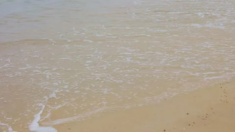 Close-up of ocean waves and white foam washing onto empty sandy beach Stock Footage 338194028