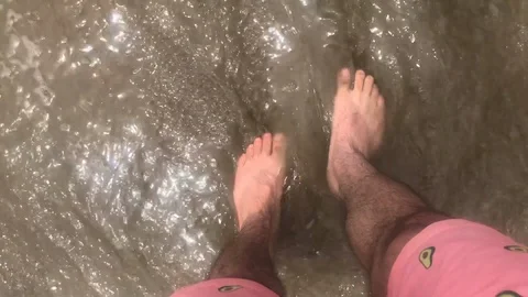 Close up of Ocean Waves crash over man's feet on the beach Stock Footage 96381275