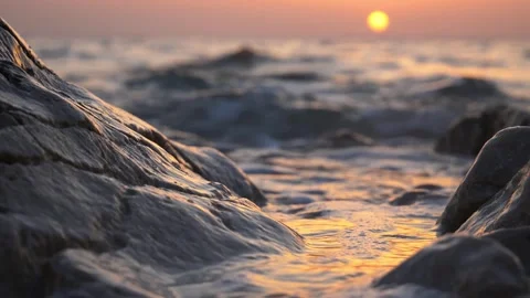 Close-Up of Ocean Waves Washing Over Coastal Rocks with Sunset in Background Stock Footage 339090827