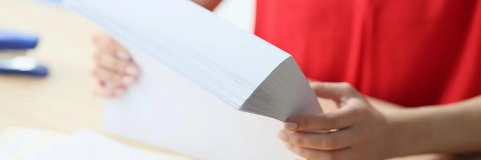 Close-up of office manager holding stack of blank paper while sitting at desk. Stock Photos