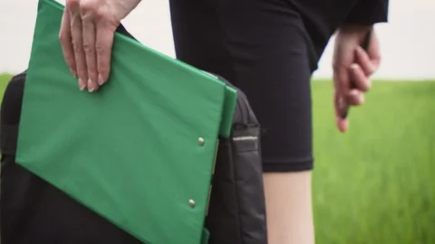 Close up of office woman with folder for sheets walking on dirt road along wheat Stock Footage 108746252