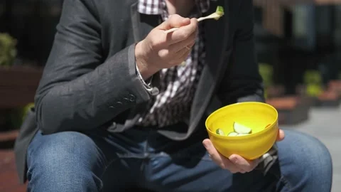 Close-up of an office worker eating a salad from a container on the street Stock Footage 155313449